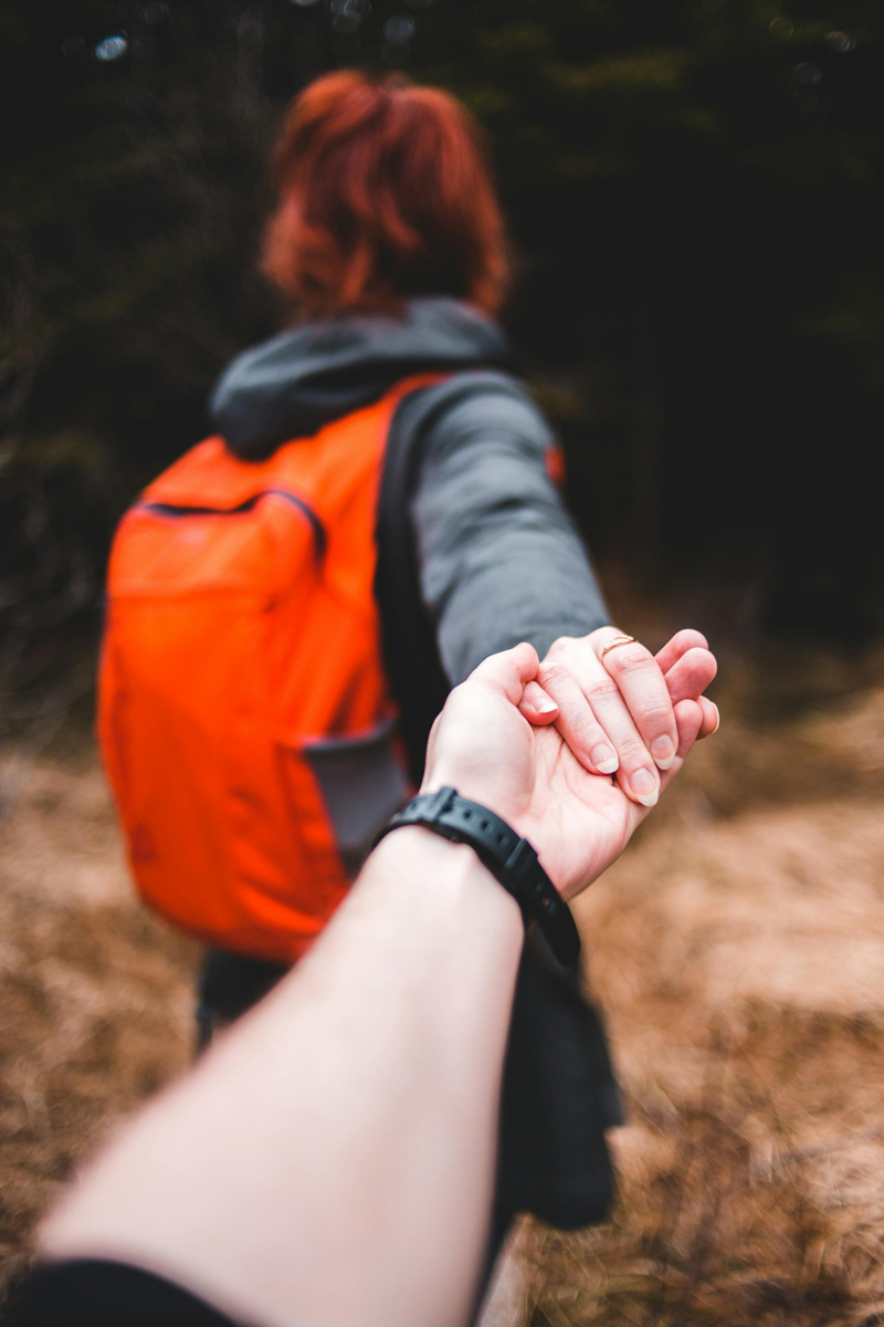 A woman hiking holding the hand of a man
