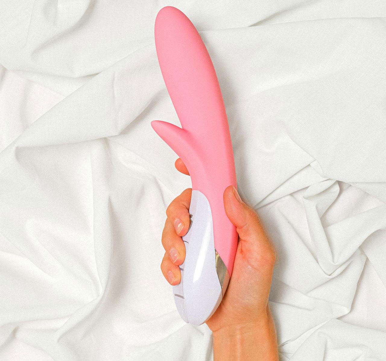 A woman's hand holding a pink rabbit style vibrator